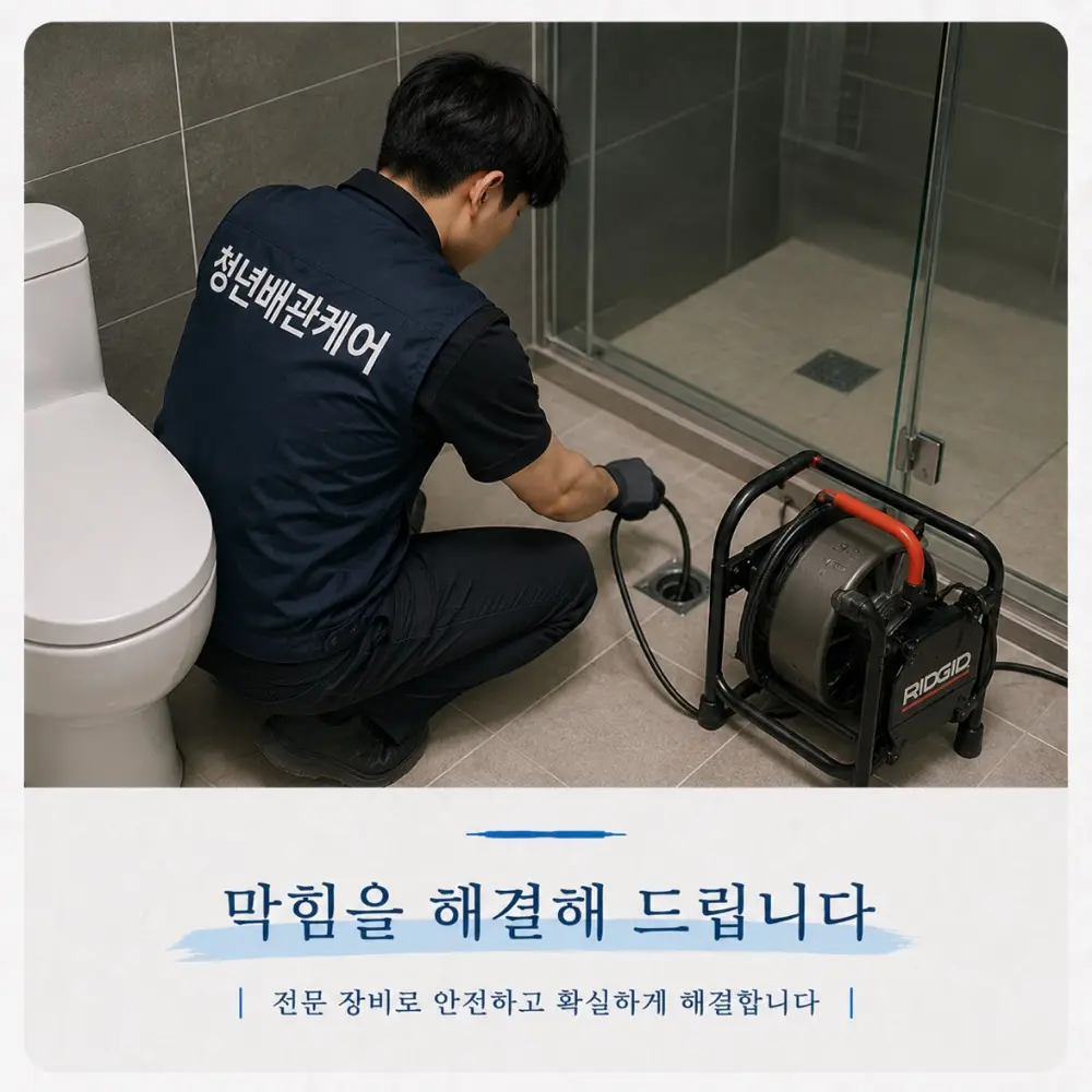 욕실 바닥 배수구에 전동 스프링 관통기를 투입해 막힘을 뚫는 하수구막힘 작업 현장